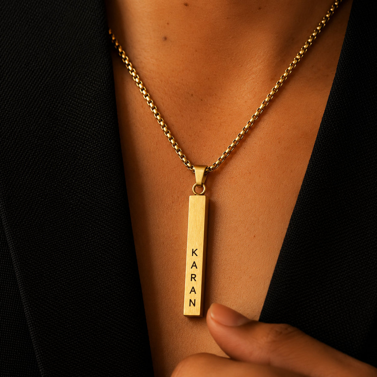 Gold vertical name bar pendant worn with a black blazer