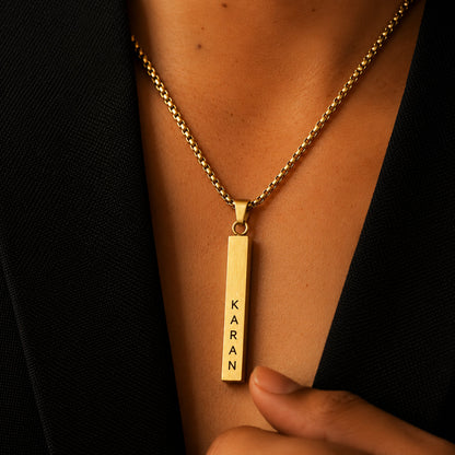 Gold vertical name bar pendant worn with a black blazer