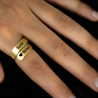 Gold couple name wrap ring worn on a finger