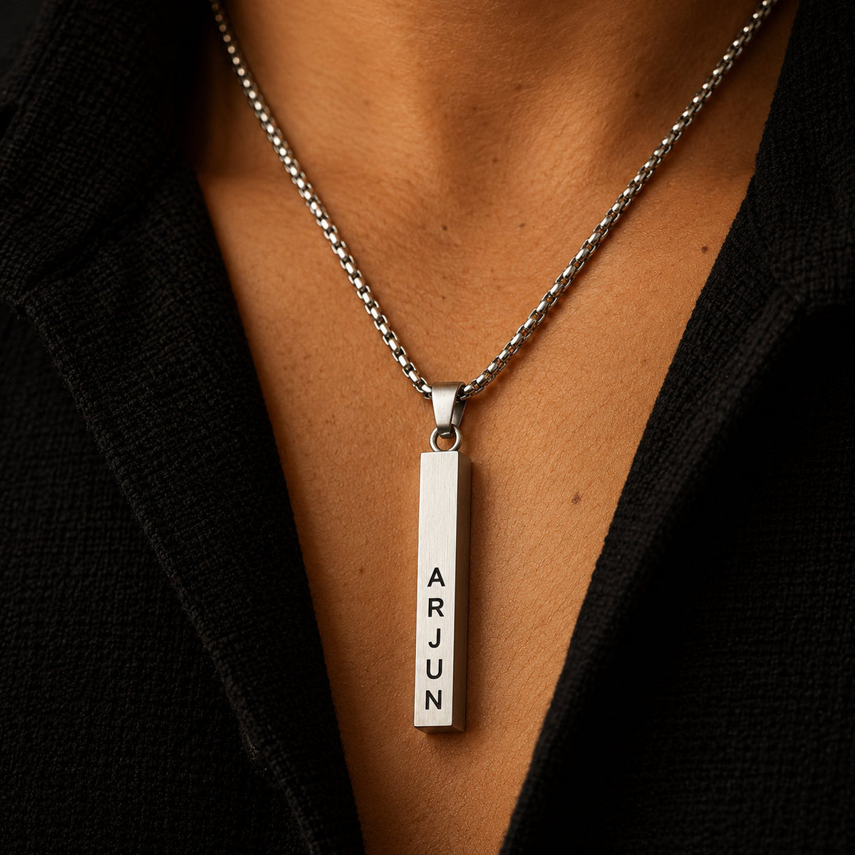 Silver vertical name bar pendant worn with a black shirt