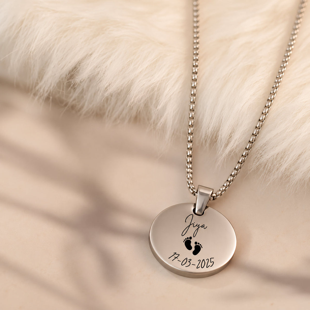 Silver baby name coin pendant with footprints on soft fur