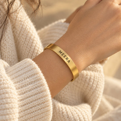 Gold name cuff bracelet worn on a woman's wrist